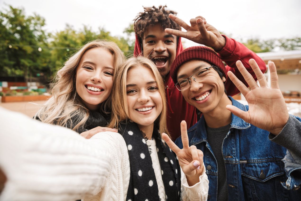 Vier Schueler machen ein Selfie und lachen gemeinsam auf einer Klassenfahrt Berlin