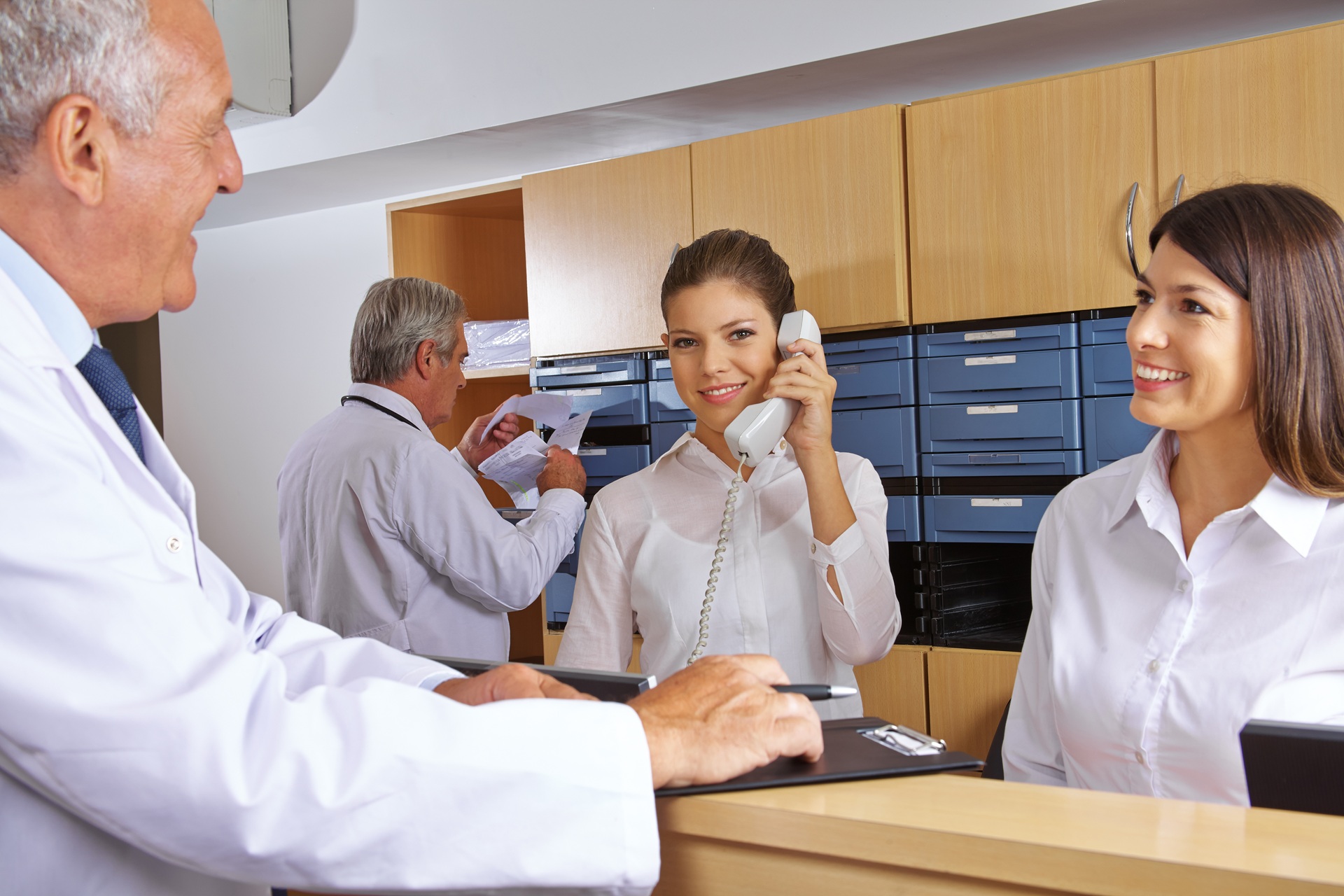 Team im Praxisempfang mit Telefon und Akten | Behandlungsstuhl