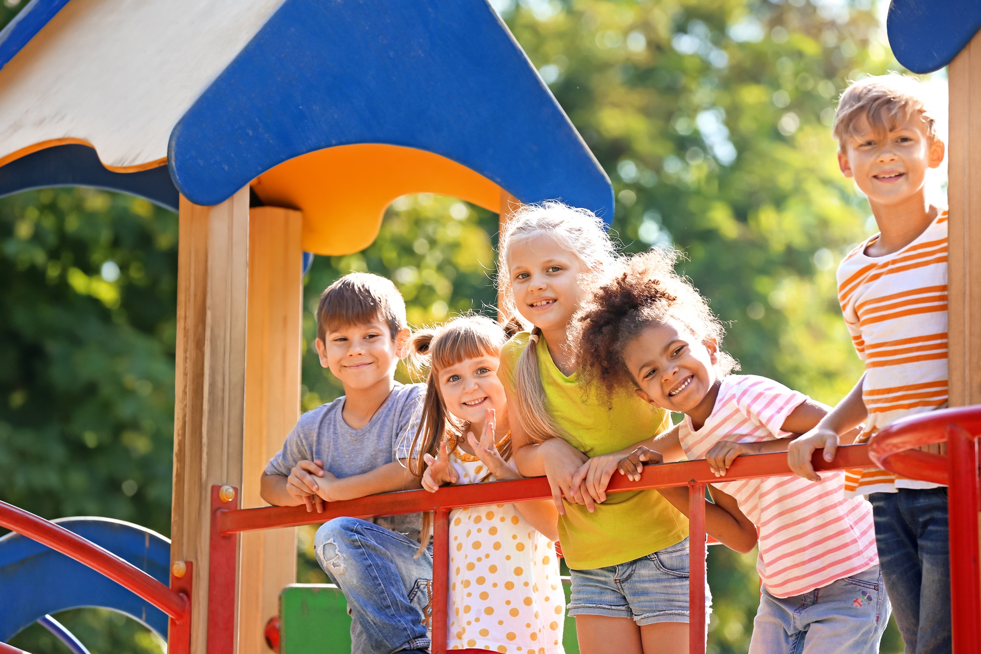 Kindergruppe lächelt am bunten Spielgerät | Spielplatzgeräte